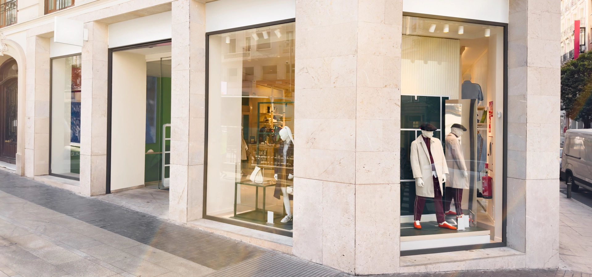 Street view of a clothing store with large glass windows displaying mannequins dressed in fashionable outfits.
